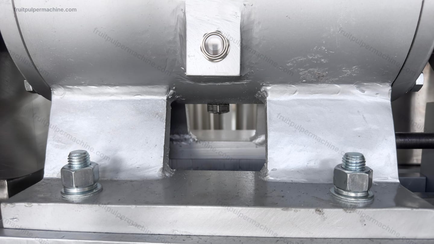 Close view of a fruit pulper inspection opening and surrounding fasteners