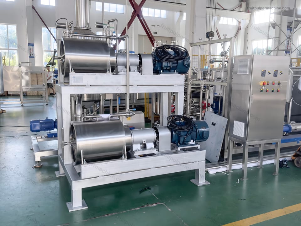 Fruit pulper housing and discharge reference Angled fruit pulper view showing cylindrical housing, drive, frame, and discharge area