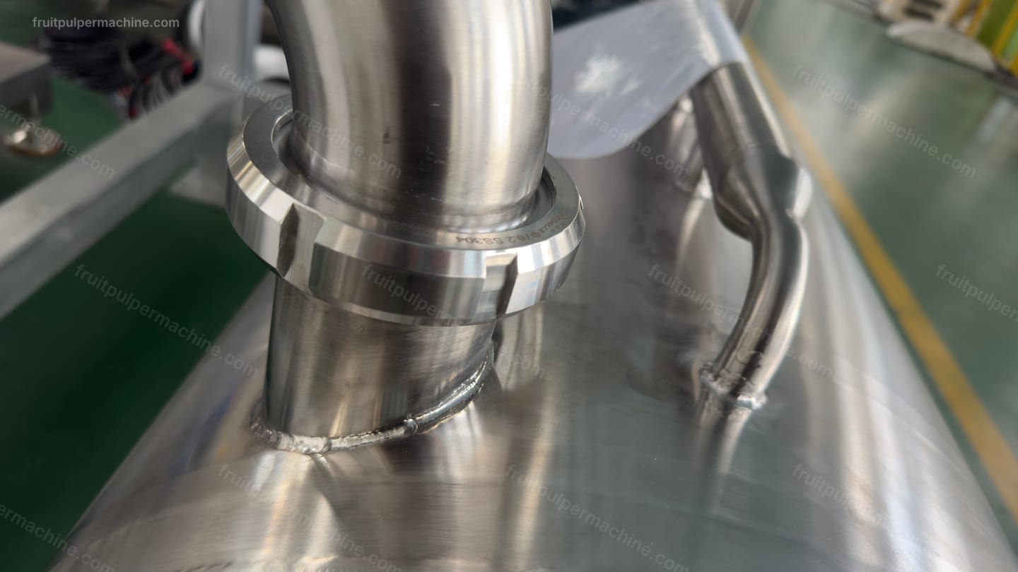 Fruit pulper process-pipe connection Close view of a stainless fruit pulper process-pipe joint at the equipment boundary